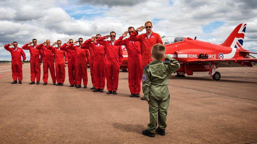 Little boy and Red Arrows crew saluting each other