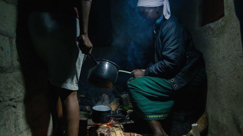 A woman using firewood to cook in Mbare township, Zimbabwe - June 2019