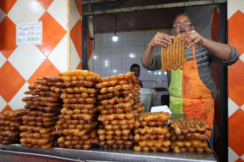 A man from Algeria sells a special dessert known as zalabiya and lemon juice at a pastry shop in Boufarik, Algeria, April 15, 2021.