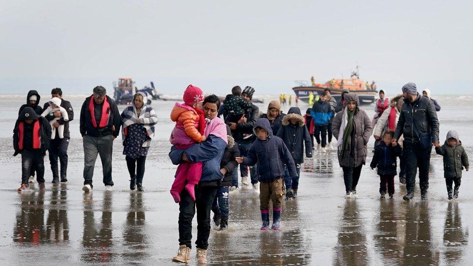 A group of people thought to be migrants walk up a beach in Kent, after being brought in from the English Channel by an RNLI lifeboat