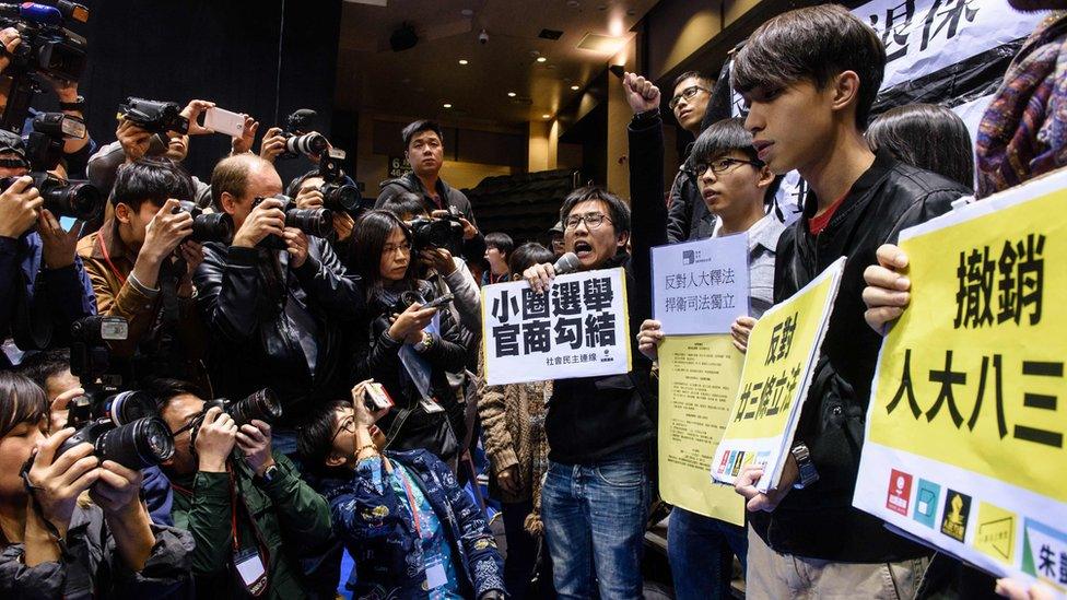 A group of protesters (R) shout slogans against former chief secretary and chief executive election candidate Carrie Lam (not seen) before the start of a press conference held by Lam in Hong Kong on 27 February 2017