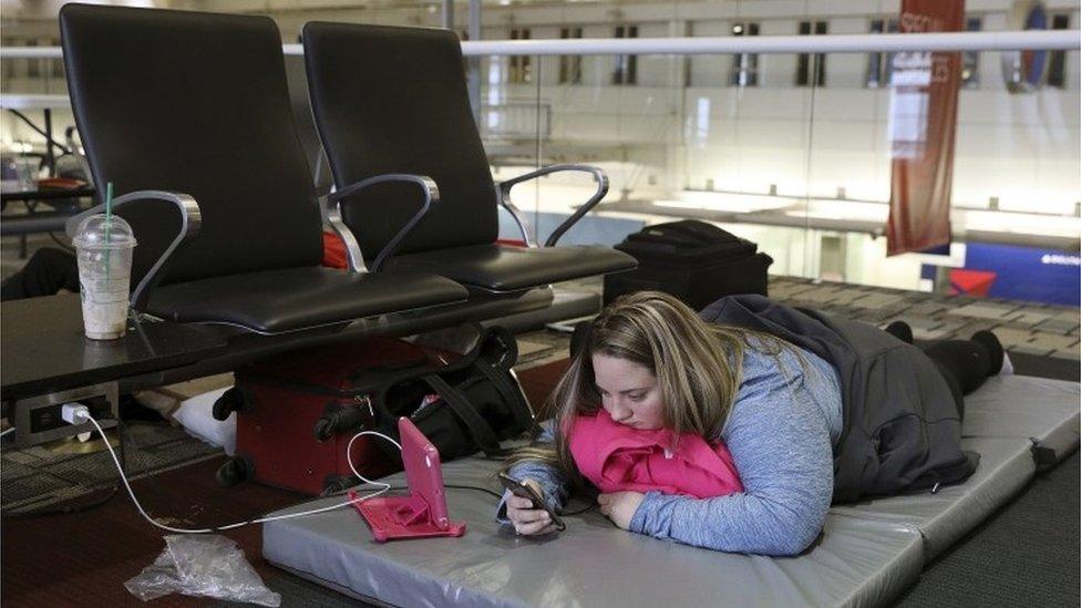 Chelsey Kalmback, 29, plays on her phone while waiting for a rescheduled flight to North Dakota after several flights were delayed or cancelled mostly due to weather, Monday, Dec. 26, 2016, at Minneapolis-Saint Paul International Airport, in Minnesota