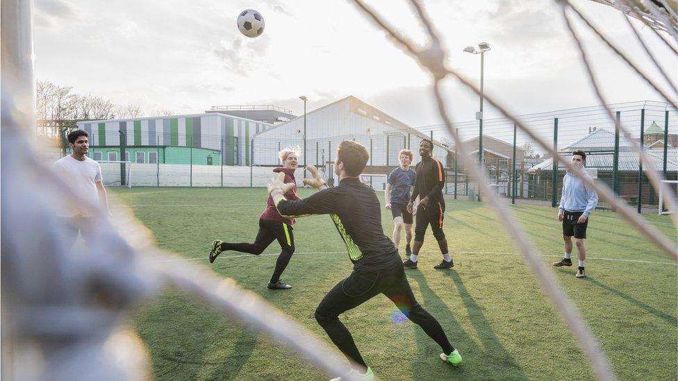 A group of young men playing football on an artificial pitch