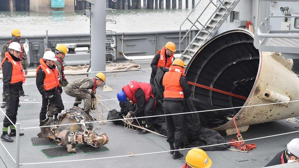 Men inspecting what are thought to be parts of a North Korean rocket