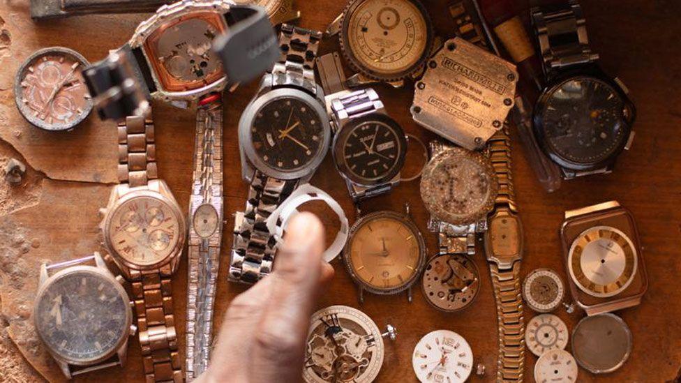 Various old wristwatches laid out on a wood table