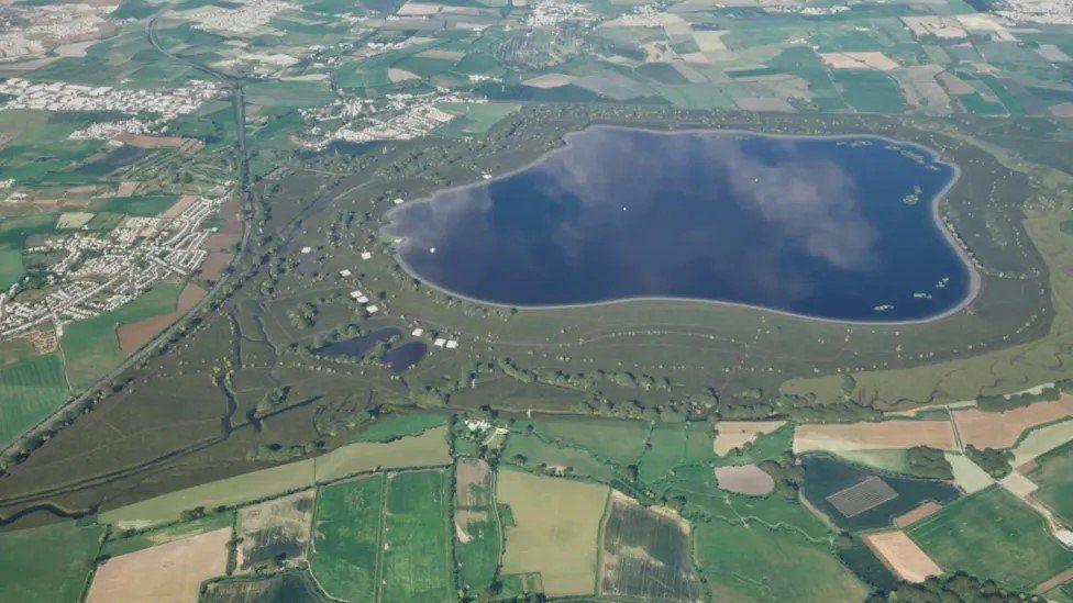 Patchwork of green fields around a puddle-shaped reservoir