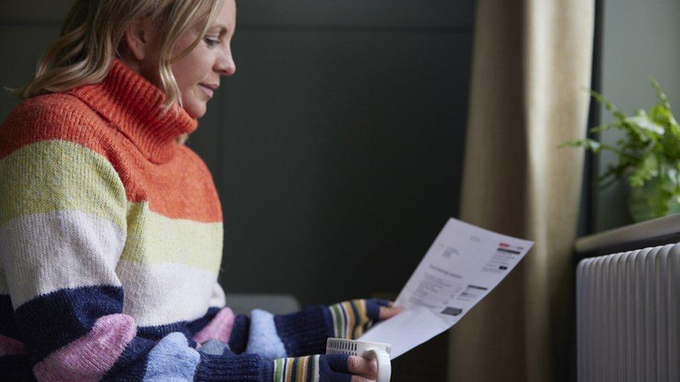 Woman in a stripy jumper looking at a bill