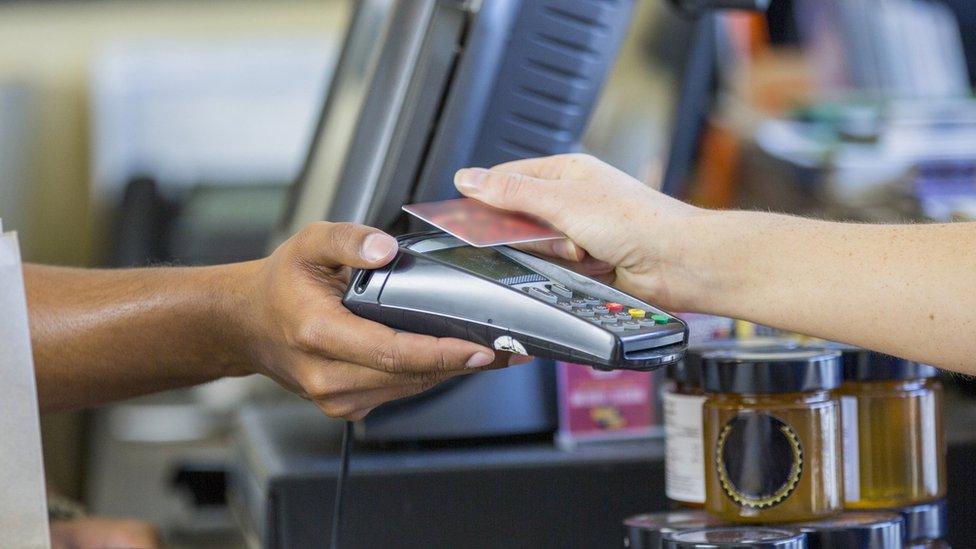 A customer uses a credit card to pay a shopkeeper