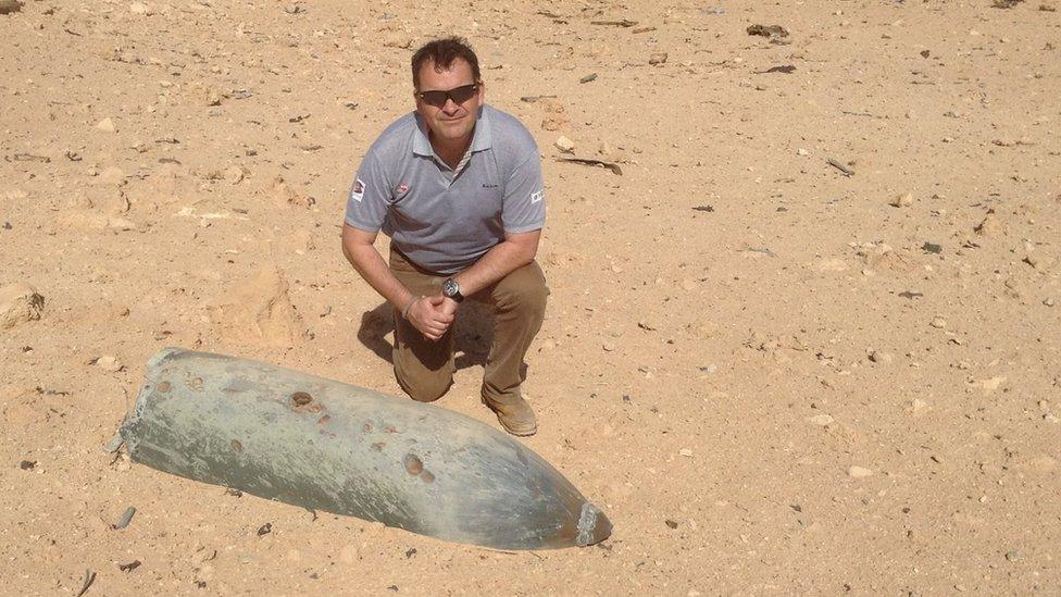 man next to inactive missile in sand