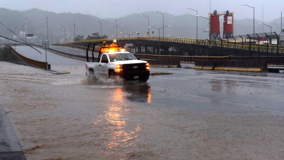 A truck drives along a flooded street in Manzanillo