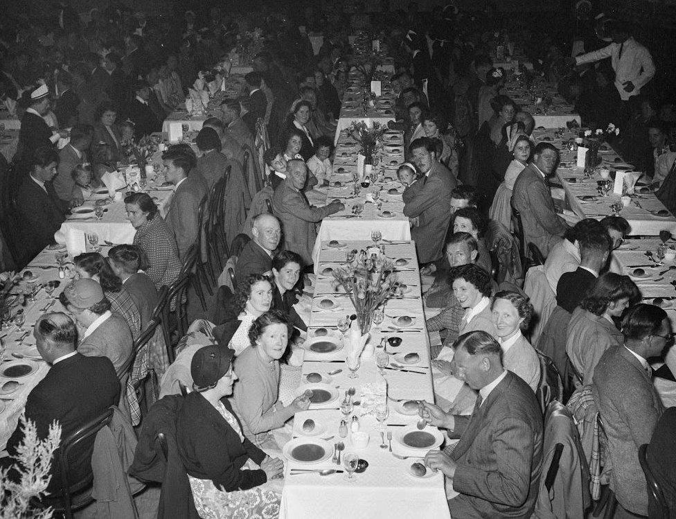 Large groups of people at tables in a hall