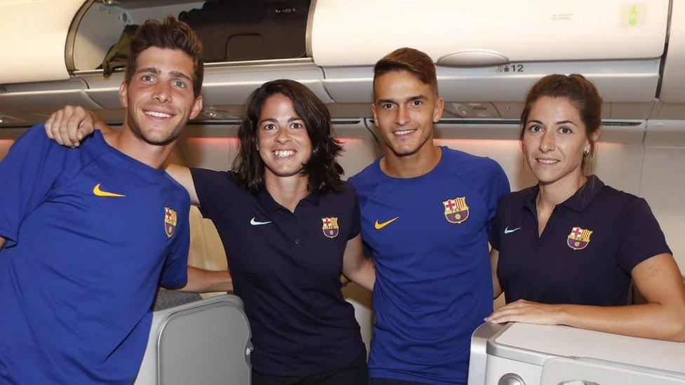 Two male and two female team members are photographed smiling together in the plane's business class