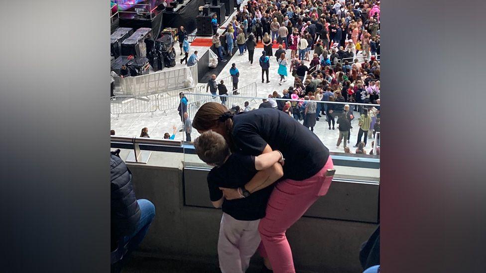 Jesse and Vanessa with their backs turned, standing overlooking the concert