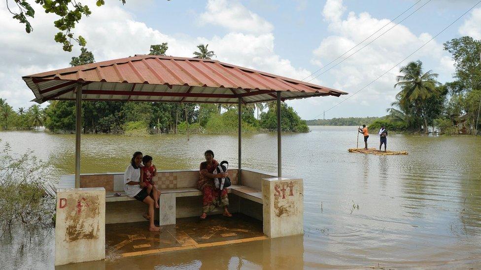 Women at a flooded bus stop