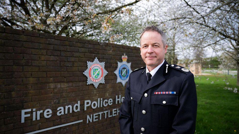 Lincolnshire Police Chief Constable Paul Gibson in uniform standing in front of a sign that says Fire and Police Headquarters