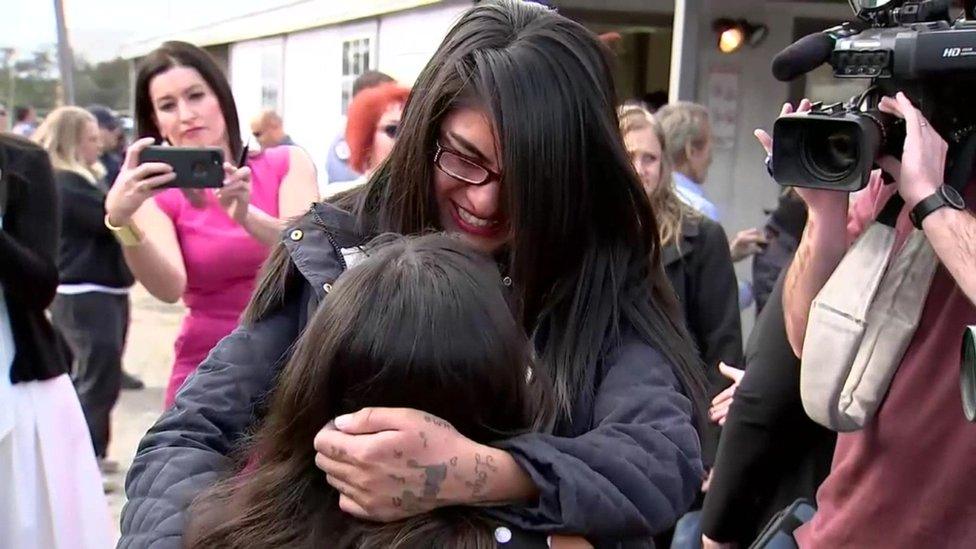 A women smiles as she hugs a young girl