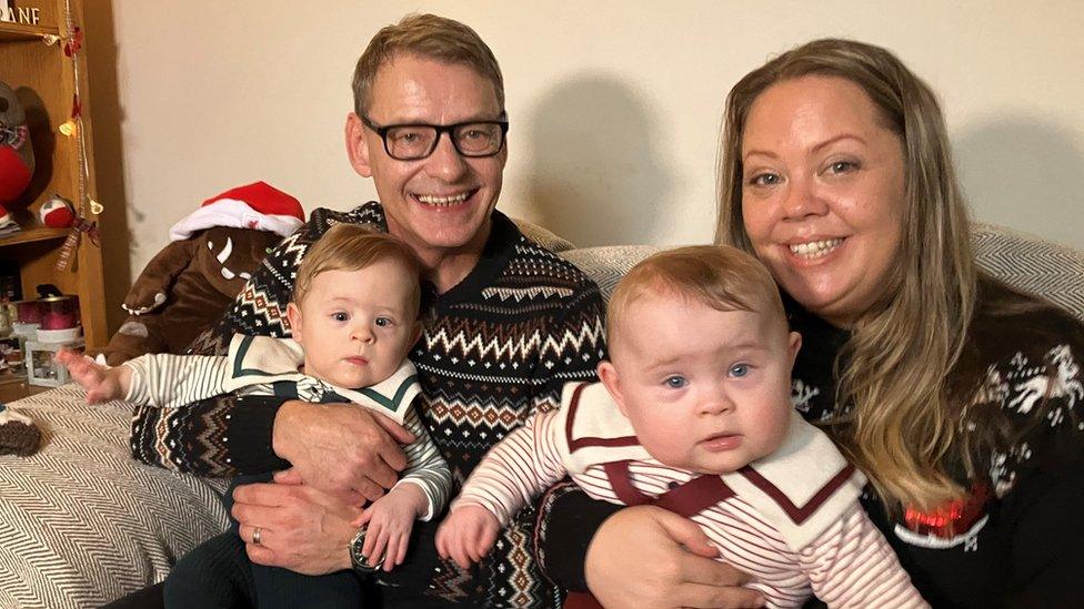 Mum, dad and the kids on the sofa in Christmas jumpers