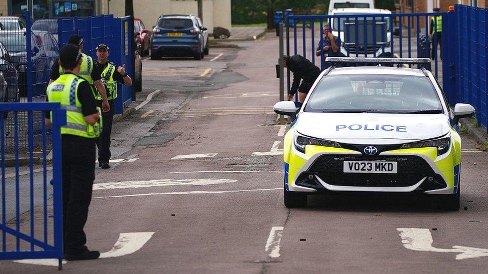 Police cars and officers on foot at the gates of a school