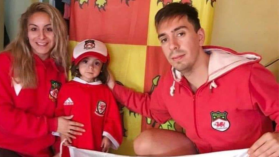 David with his partner and daughter in Wrexham and Wales merchandise. the flag of Owain Glyndŵr carried into battle is behind them