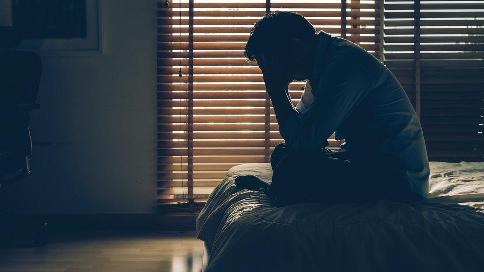 Distressed looking man sitting on bed