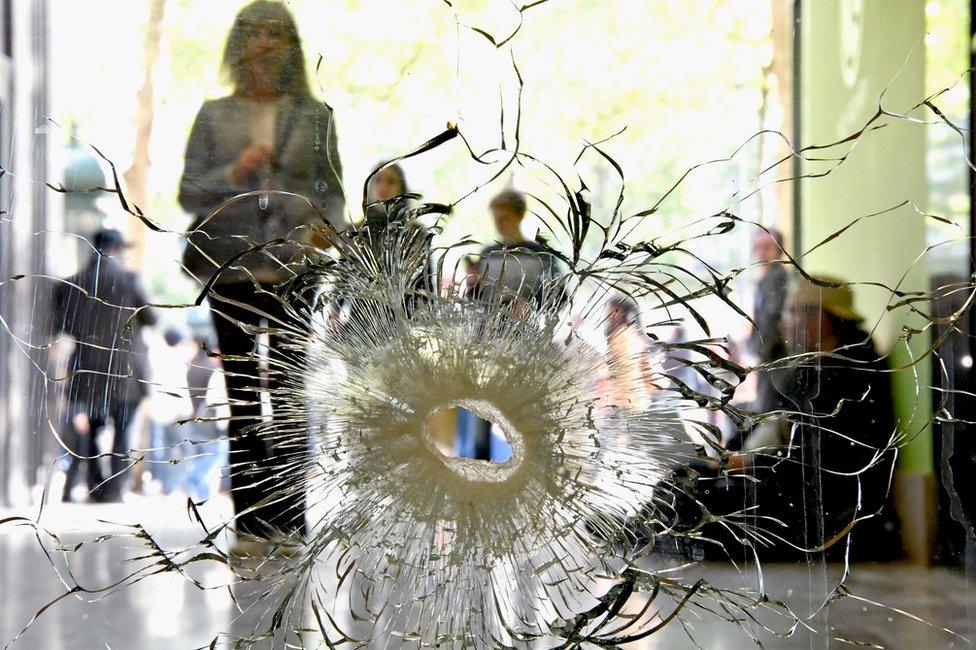 People look at a bullet hole in a window near to the Marks and Spencer on the Champs Elysees in Paris following the shooting of a police officer, 21 April