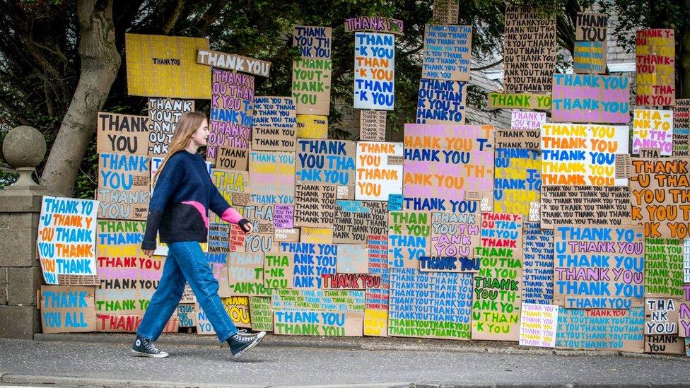 woman walking past thank you nhs signs