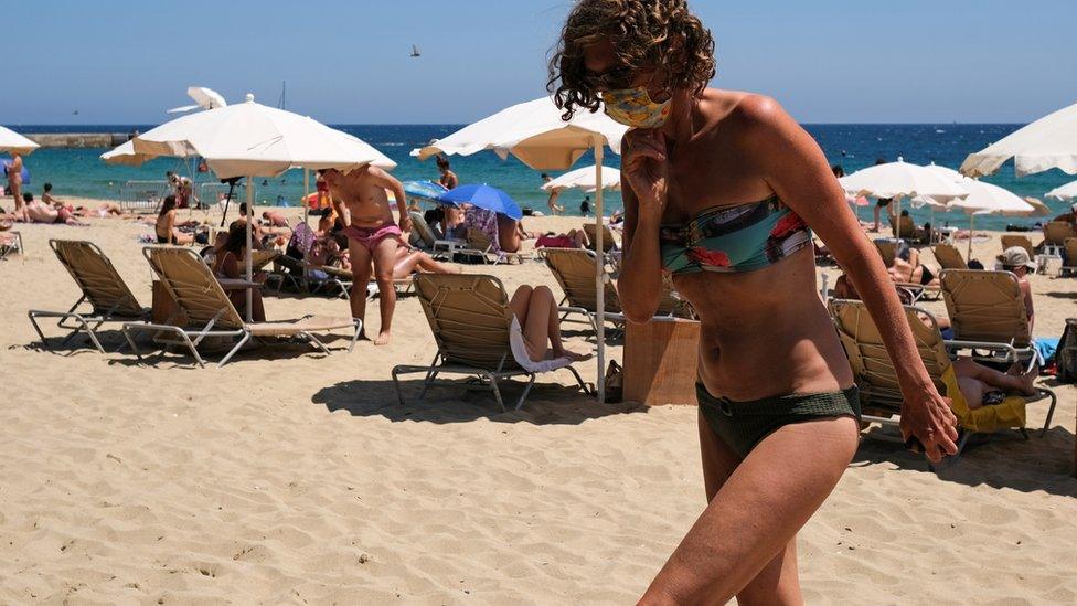 A woman wears a face covering on a beach