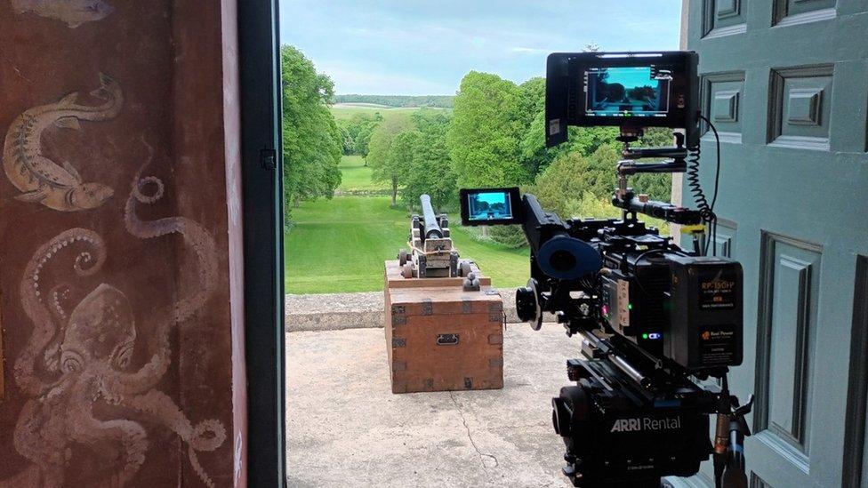 The cannon in the doorway of a stately home with a camera behind