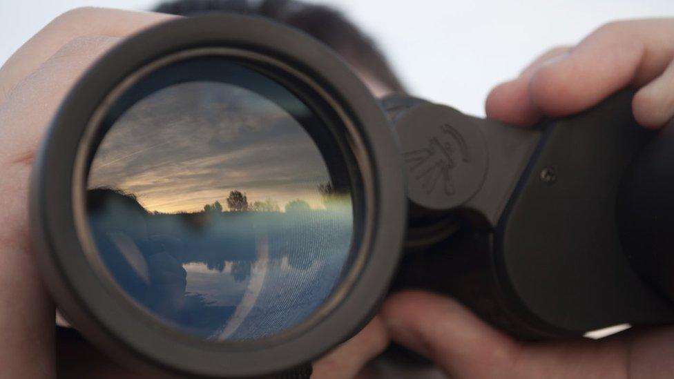 looking through binoculars