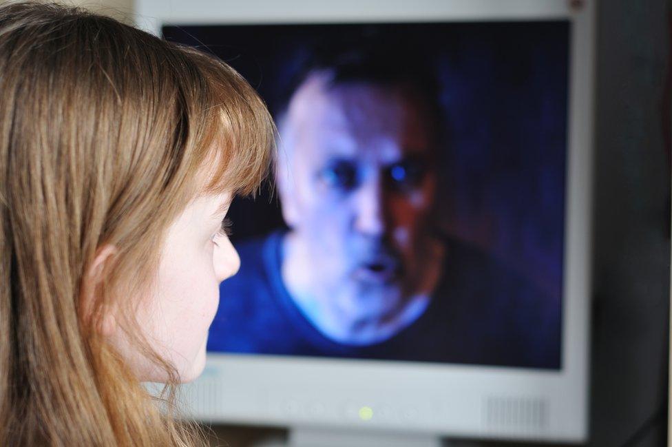 Girls looks at man's face on computer screen