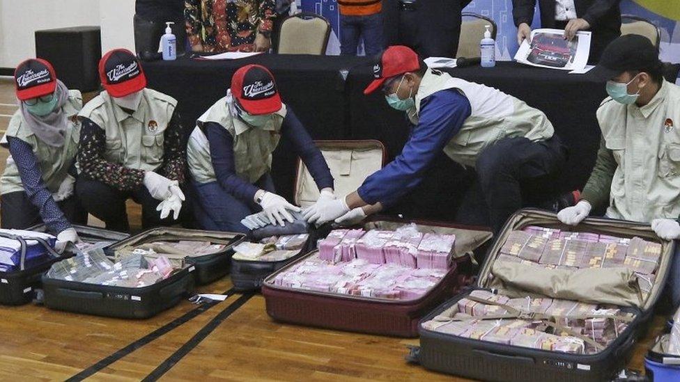 Officers show the suitcases filled with cash