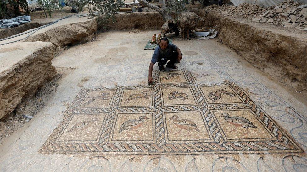 Salman al-Nabahin cleaning the mosaic floor discovered on his farm in Gaza