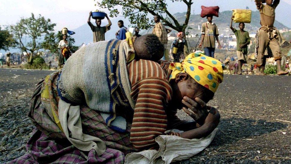 A Rwandan woman collapses with her baby on her back alongside the road connecting Kibumba refugee camp and Goma in this July 28, 1994