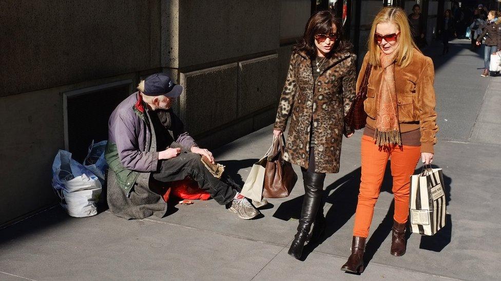 Women walk by a panhandler along Madison Avenue, one of Manhattan's premier shopping and residential streets on November 1, 2011 in New York City.