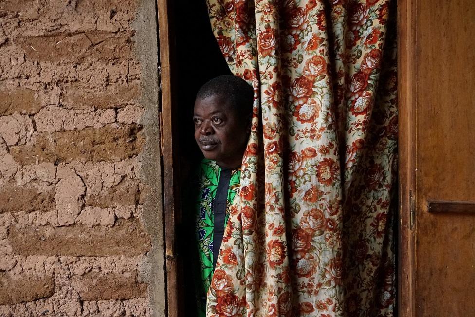 Man looking through a curtain