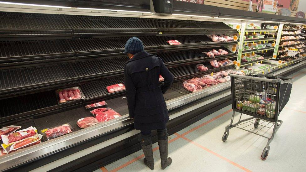 A shopper looks at empty shelves.