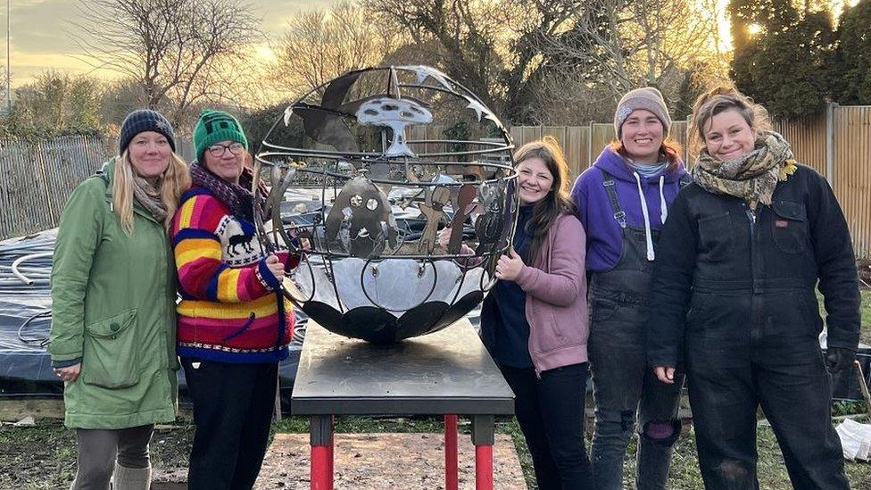 Group of women stood next to a metal sphere