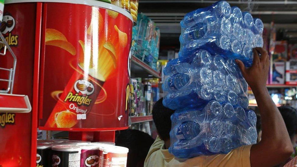 man with three stacks of bottled water on his shoulder