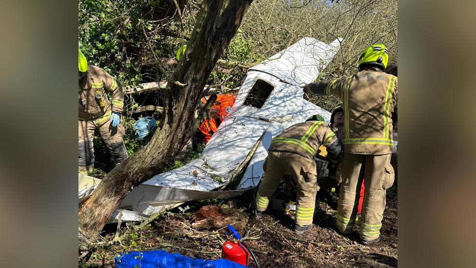 Emergency service workers attend the scene of the crash in woodland