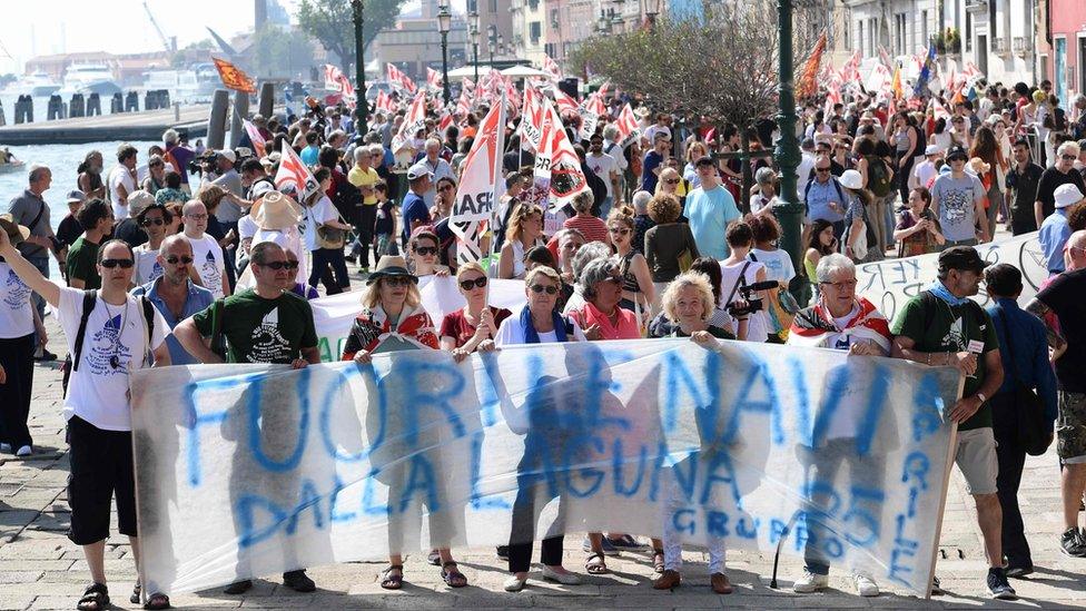 People hold a banner that reads "Ships out of the lagoon" during a demonstration by the No Great Ships movement