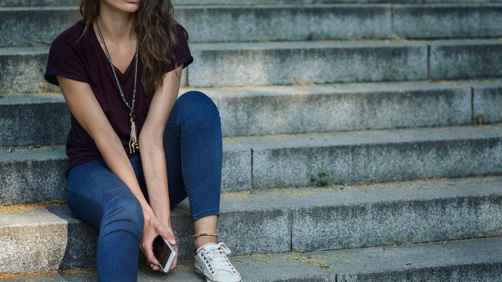 girl sat on steps holding phone