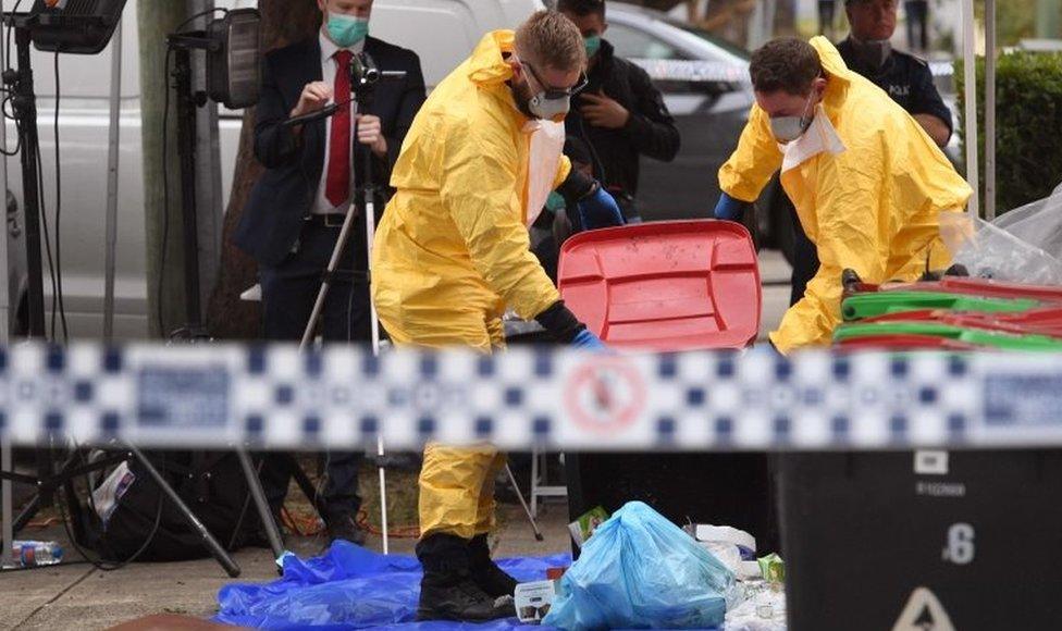 Police officers study the contents of a household bin as part of their investigation in Sydney