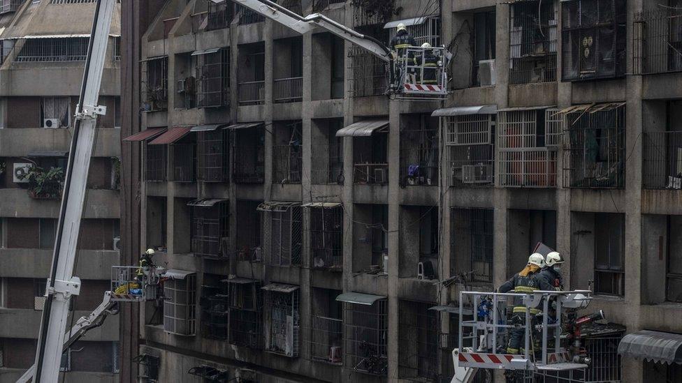 Firefighters search for victims from a residential building in the wake of a fire on 14 October 2021, in Kaohsiung, Taiwan