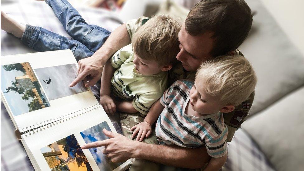 Dad showing his sons photos from Iraq