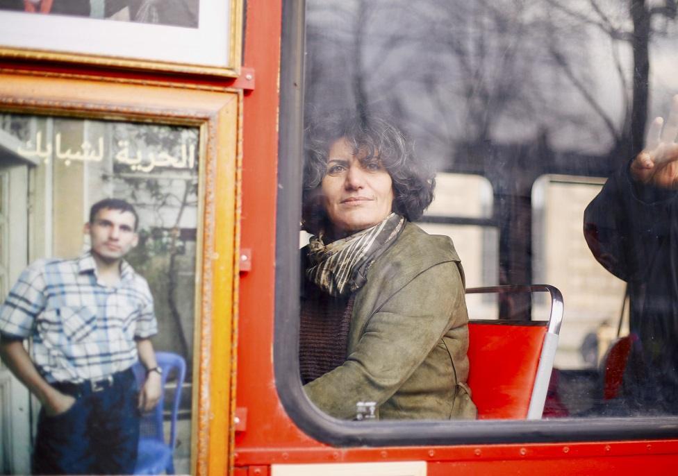 A Syrian refugee looks out of a bus a window