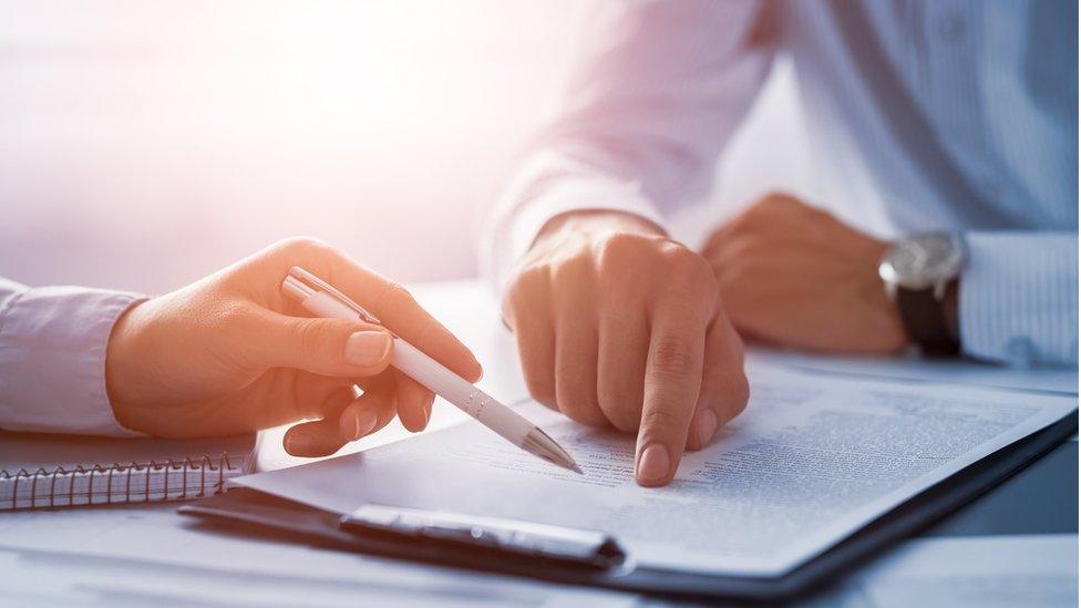 men at desk pointing at a work document