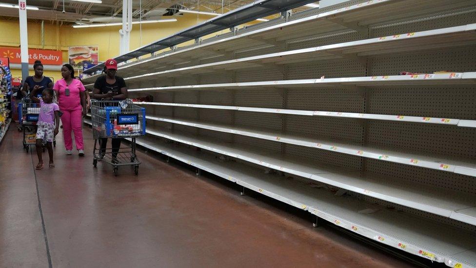 People walk past empty shelves in store