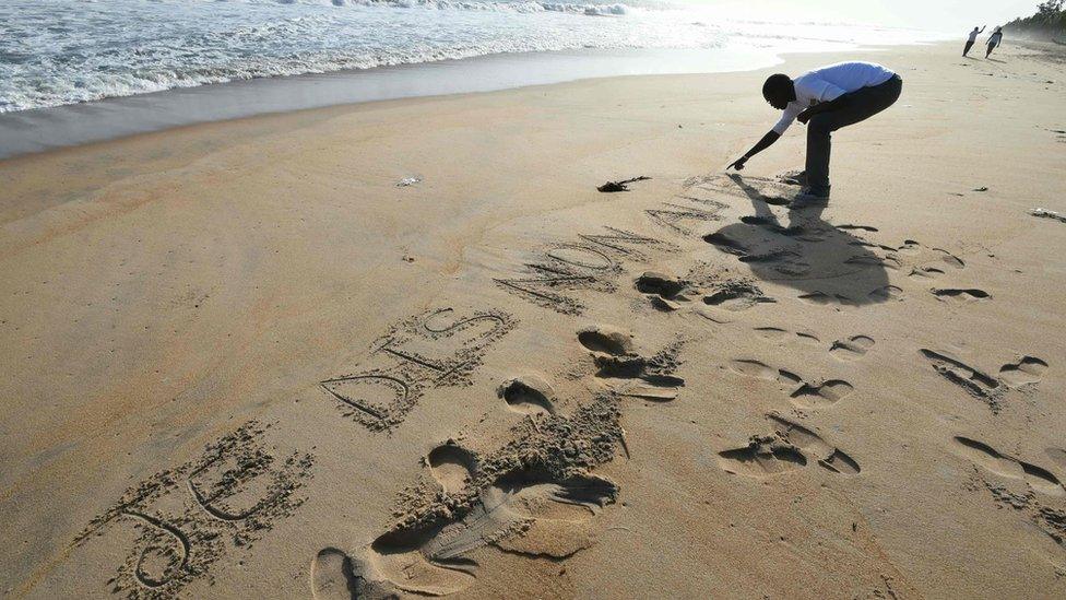 A man scratches in the sand the words, "I say no to terrorism" close to the Hotel Etoile du Sud, in Grand-Bassam some 40 kms east of Abidjan on March 16, 2016, three days after gunmen attacked the Ivory Coast resort town popular with Ivorians and Westerners, killing fourteen civilians and two soldiers