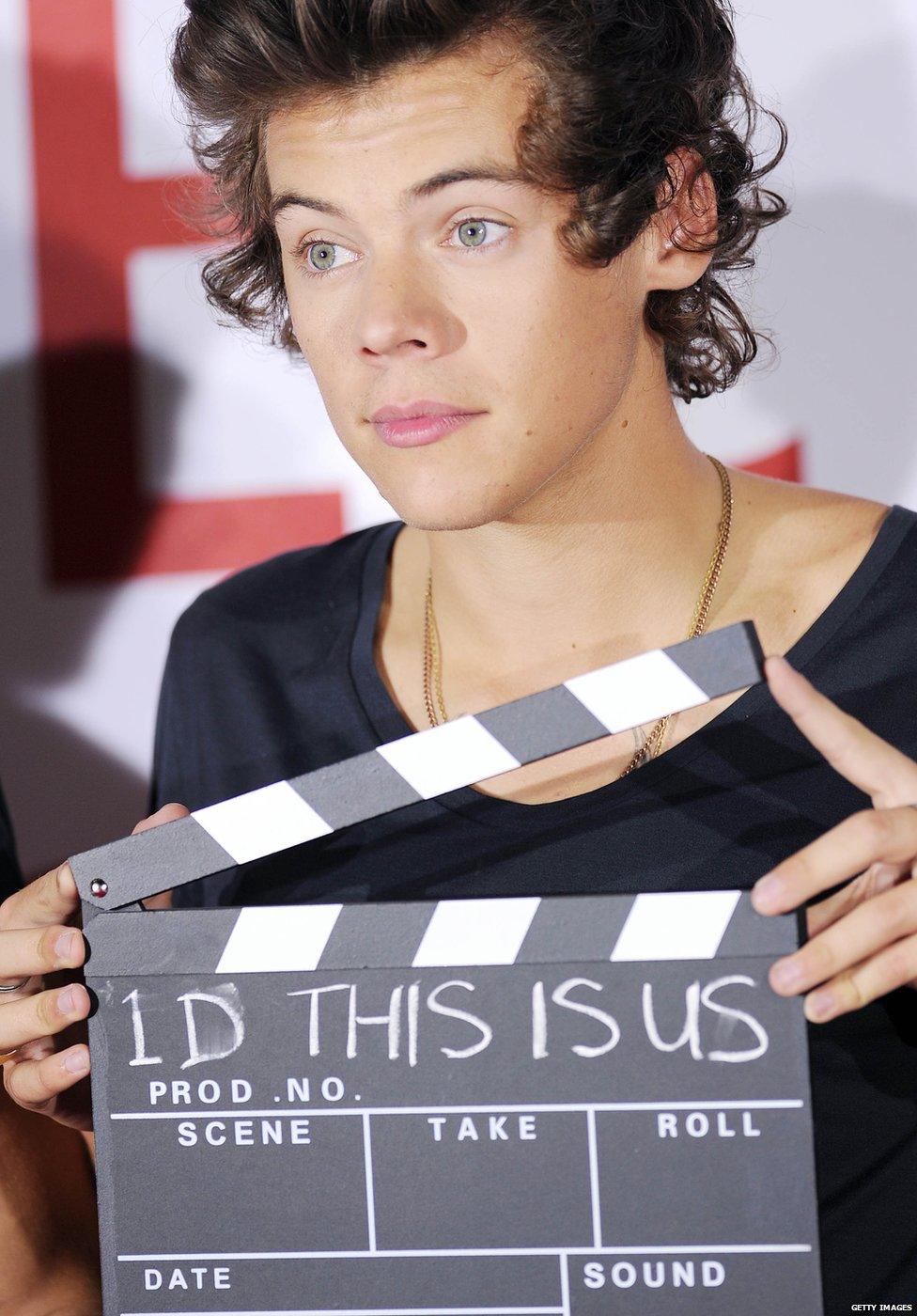 Harry Styles holding up a clapper board at the premier of the 1D movie 'This Is Us'