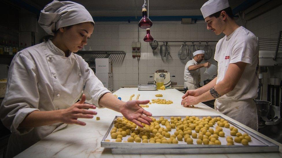 A female and male cook making pastry in a professional kitchen